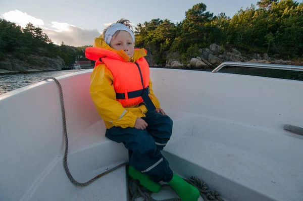 Sitting on a bow of a boat child riding back home — Stock Photo, Image