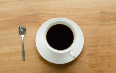 Tahta arka planda beyaz bir fincanda bir fincan kahve.