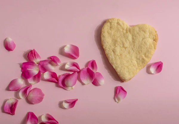 Het Een Hartkoekje Een Roze Achtergrond Met Rozenblaadjes — Stockfoto