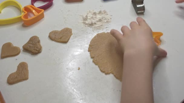 Le mani da bambini ritagliano biscotti a forma di cuore da pasta — Video Stock