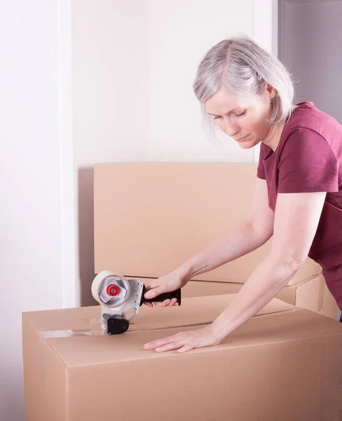 Woman closing a moving box in a house