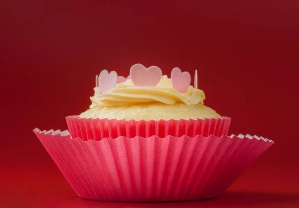 Schöner Valentin Vanille Cupcake mit essbaren Herzen Stockfoto