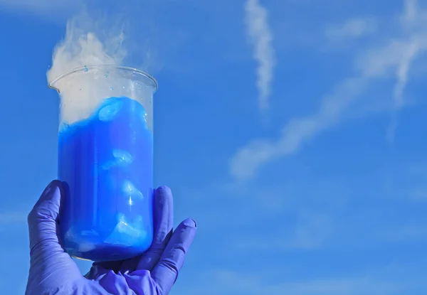 White smoke comes from a beaker with blue solution of fluorescein after addition of dry ice. Chemist demonstration experiment.