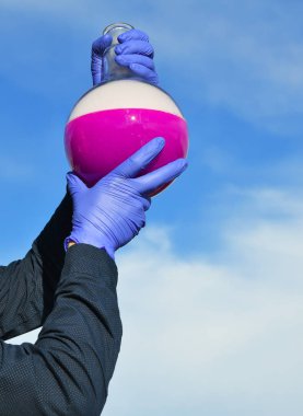 Bilim adamı elinde kırmızı floresan solüsyonlu matara tutuyor. Kuru buz kabarcıklarla ve beyaz dumanla sonuçlanır. 