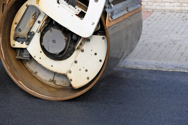Compaction of asphalt coating with a roller during repair of the carriageway of the city street.