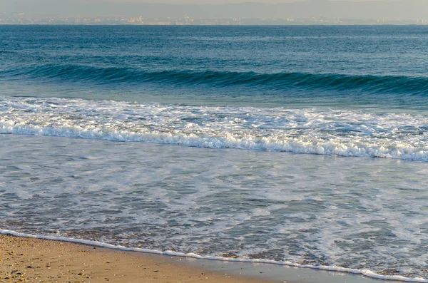 Gentle blue waves lapping on sandy beach