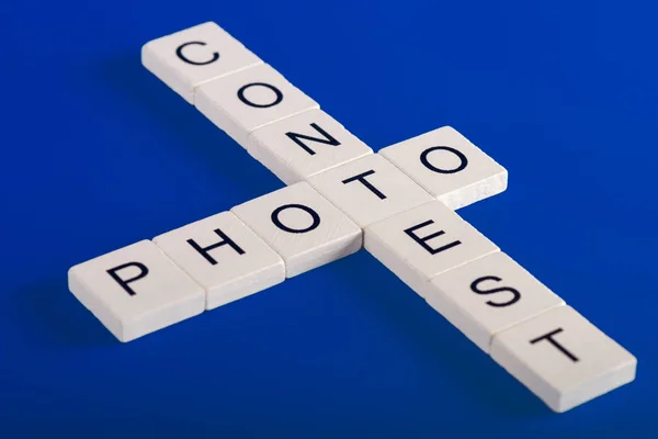 Photo Contest phrase of wooden white blocks, blue background