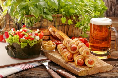 Puf böreği salata ve bira ile pişmiş sosisli sandviç sosis haddelenmiş