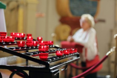 Yaşlı kadın diz üzerinde bir kilisede dua