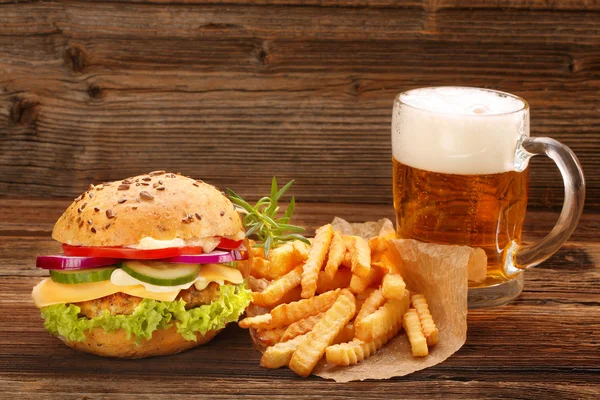 Čerstvé chutné burger s hranolky a pivo na dřevěný stůl — Stock fotografie