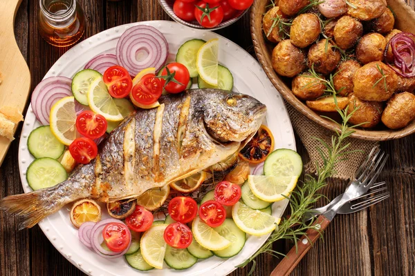 Жареная рыба с жареным картофелем и овощами на тарелке — стоковое фото