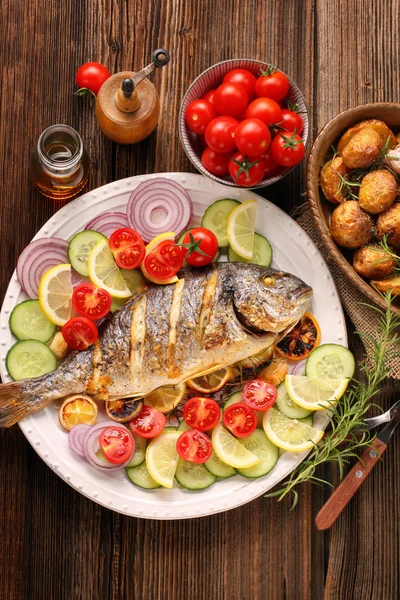 Жареная рыба с жареным картофелем и овощами на тарелке — стоковое фото