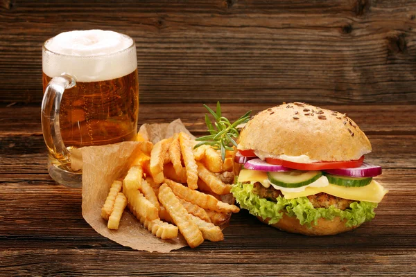 Čerstvé chutné burger s hranolky a pivo na dřevěný stůl — Stock fotografie