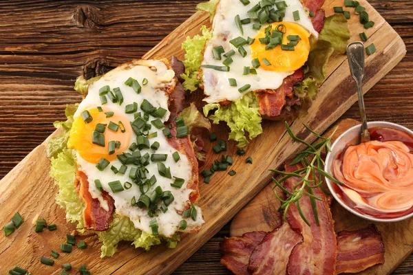 Smörgås med stekt bacon, ägg och grönsaker på trä backgrou — Stockfoto