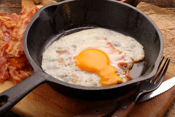 Sıcak jambon parçaları bir dökme demir tavada kızarmış yumurta