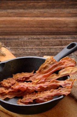Bir dökme demir tavada sıcak kızarmış domuz pastırması parçaları
