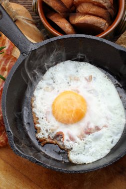 Sıcak jambon parçaları bir dökme demir tavada kızarmış sıcak yumurtayla