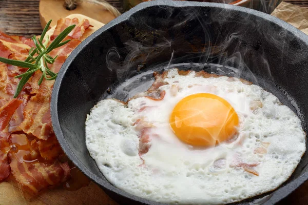 Gorący jajko sadzone z boczkiem gorące kawałki na patelni żeliwnych — Zdjęcie stockowe