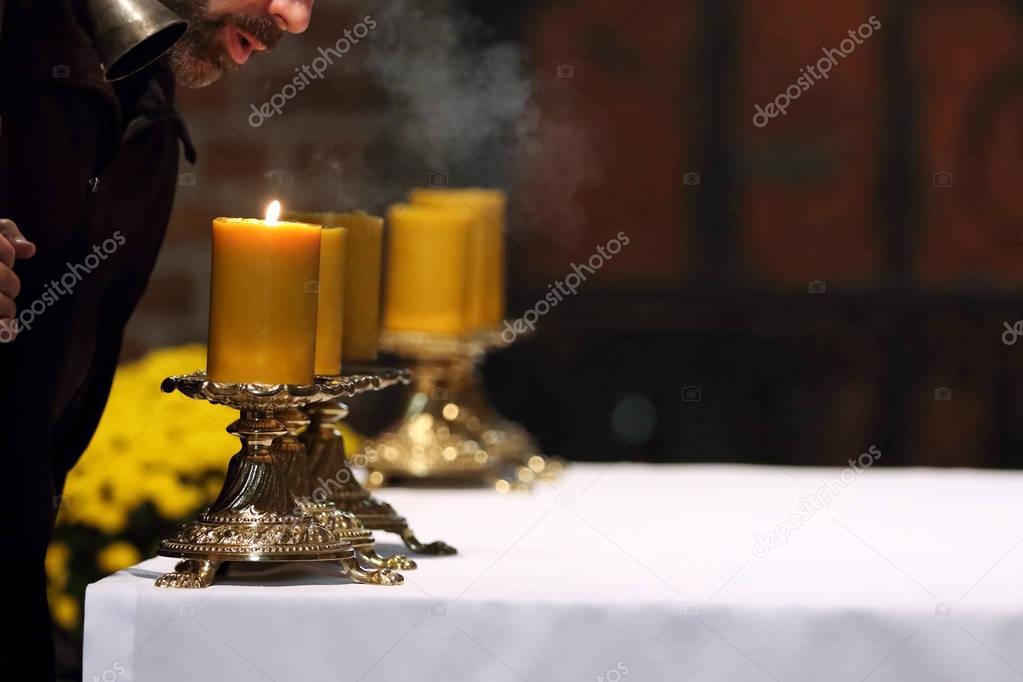 The priest puts out the candles on the altar after Mass in the c