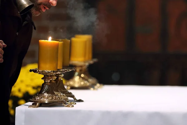 El sacerdote apaga las velas en el altar después de la misa en el c —  Fotos de Stock