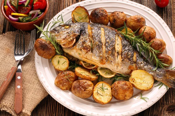 Gegrilde vis met gebakken aardappelen en groenten op de plaat — Stockfoto