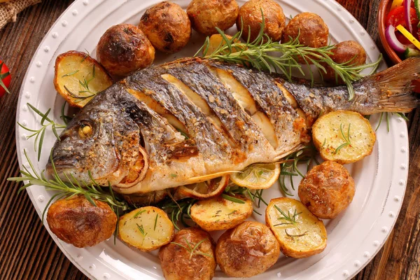 Gegrilde vis met gebakken aardappelen en groenten op de plaat — Stockfoto