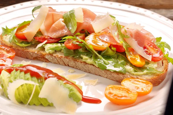 Sandwich à l'avocat sur pain frais avec jambon de roquette tomate et fromage — Photo