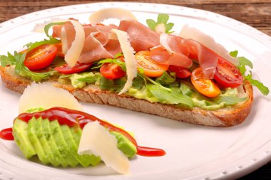 Roka ham domates ve chee ile taze ekmek üzerinde avokado sandviç