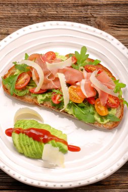 Roka ham domates ve chee ile taze ekmek üzerinde avokado sandviç