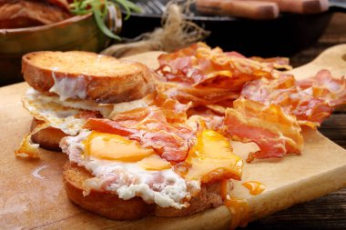 Sahanda yumurta ve ahşap adam sıcak domuz pastırması parçaları ile sandviç