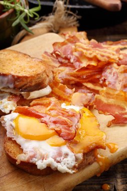 Sahanda yumurta ve ahşap adam sıcak domuz pastırması parçaları ile sandviç