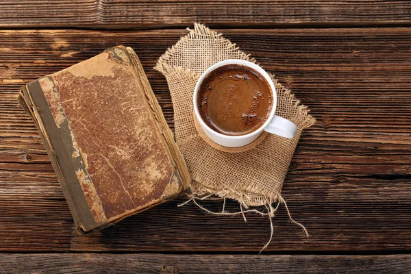 Старая книга и чашка кофе на деревянном фоне — стоковое фото