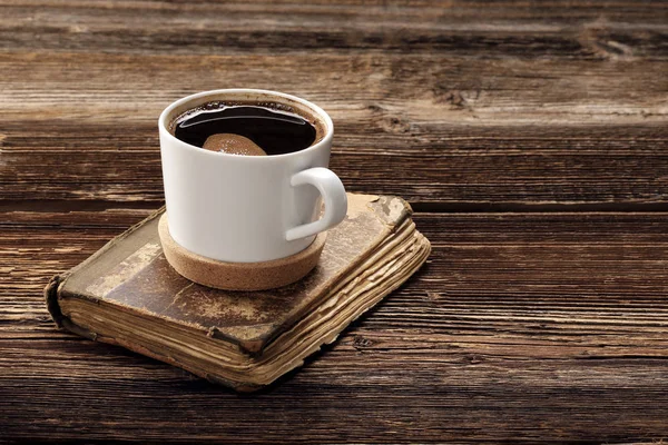 Старая книга и чашка кофе на деревянном фоне — стоковое фото