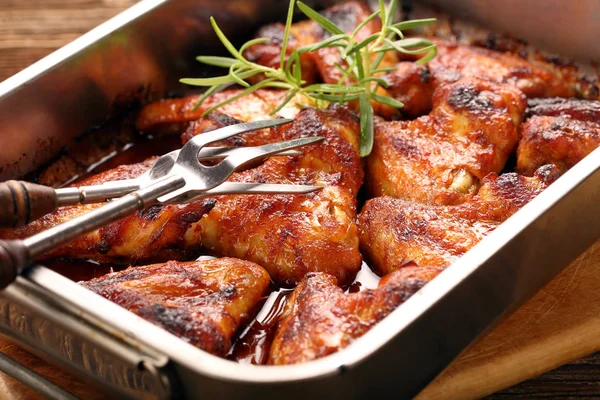 Chicken wings baked in a pan on wooden background — Stock Photo, Image