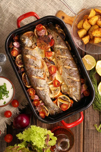 Gebakken vis met groenten en aardappelen in de pan — Stockfoto