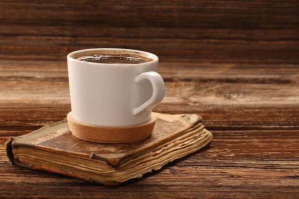 Чашка кофе и старая книга на деревянном фоне — стоковое фото