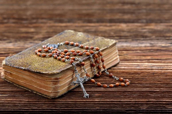 Very old prayer book and vintage rosary on wooden background — Stock Photo, Image