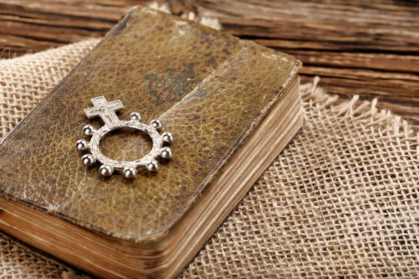 Very old prayer book and ten rosary on wooden background — Stock Photo, Image