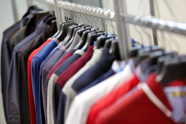 Camisolas masculinas e jaquetas penduradas em guarda-roupa — Fotografia de Stock