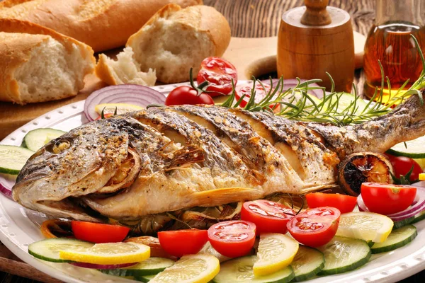 Рыба-гриль с багетом и овощами на тарелке — стоковое фото