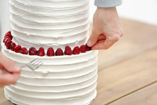 Pastelero decora pastel de boda blanco — Foto de Stock