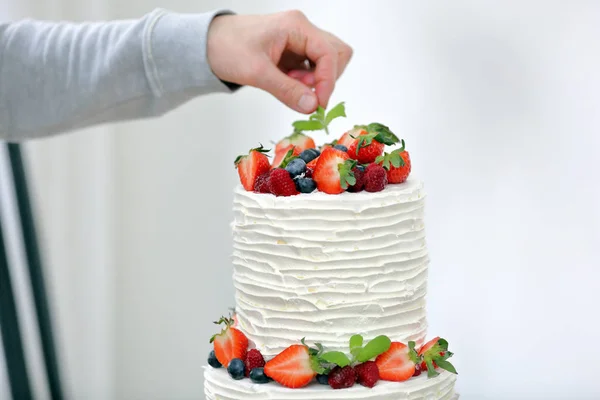 Confeiteiro decora bolo de casamento branco — Fotografia de Stock