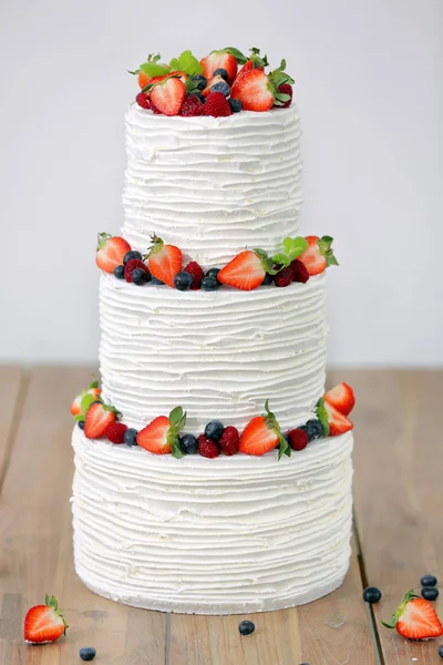 Three parts naked wedding cake with fruits and berries