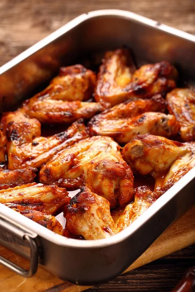 Chicken wings baked in a pan on wooden background — Stock Photo, Image