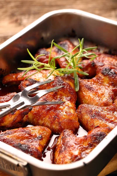Chicken wings baked in a pan on wooden background — Stock Photo, Image