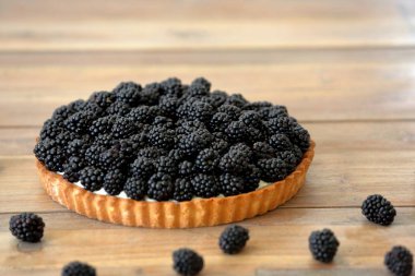 Ahşap arka plan üzerinde taze böğürtlen ile tart