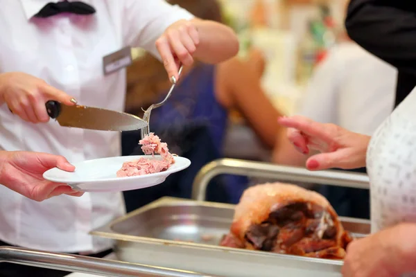 Kelner w plasterkach i serwuje pieczone mięso na imprezie — Zdjęcie stockowe
