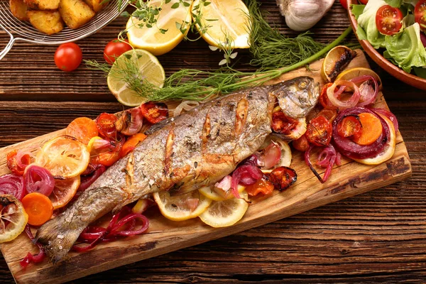 Pesce alla griglia con patate su fondo di legno — Foto Stock