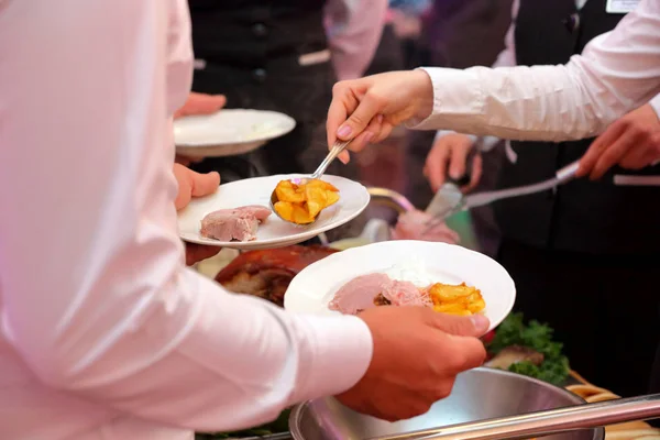 Kelner serwowane są pieczone mięsa i pieczone ziemniaki na imprezie — Zdjęcie stockowe