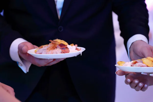 waiter serves roasted meat and baked potatoes at the party